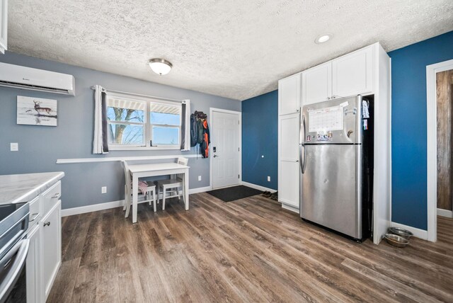 kitchen featuring white cabinetry, a textured ceiling, stainless steel fridge, and a wall unit AC