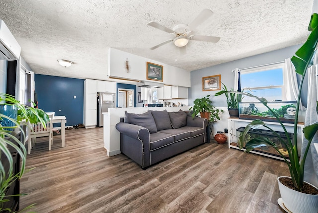 living room with a wall mounted air conditioner, dark wood-type flooring, a textured ceiling, and ceiling fan
