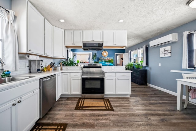 kitchen with sink, dark wood-type flooring, stainless steel appliances, white cabinets, and an AC wall unit