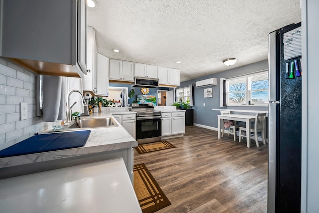 kitchen featuring sink, white cabinetry, stainless steel appliances, a wall mounted AC, and kitchen peninsula