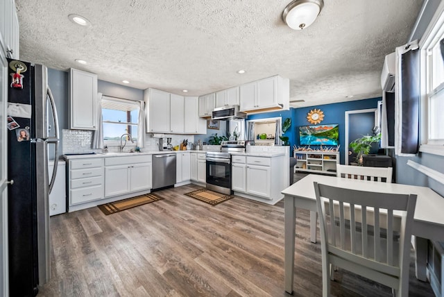kitchen featuring sink, white cabinetry, appliances with stainless steel finishes, dark hardwood / wood-style floors, and decorative backsplash