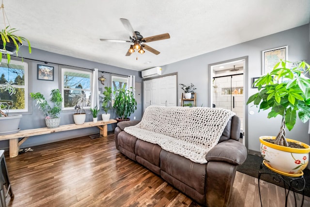 living room featuring dark hardwood / wood-style flooring, a wall mounted air conditioner, and ceiling fan