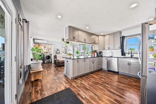 kitchen with gray cabinets, stainless steel appliances, tasteful backsplash, washing machine and clothes dryer, and kitchen peninsula