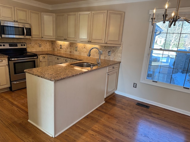 kitchen with sink, appliances with stainless steel finishes, hanging light fixtures, light stone counters, and tasteful backsplash