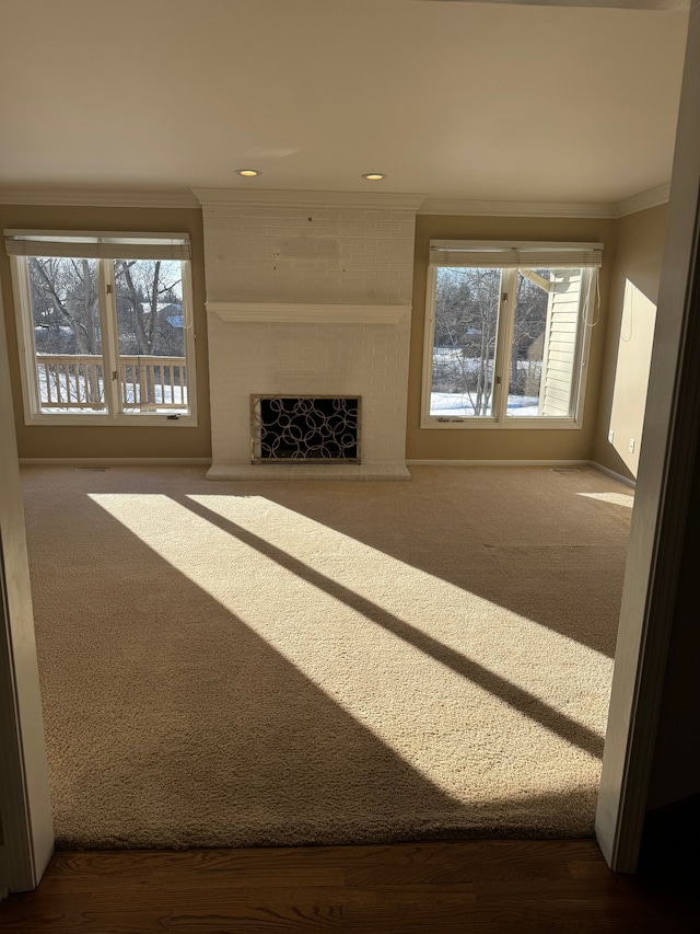 unfurnished living room featuring crown molding, carpet floors, and a fireplace