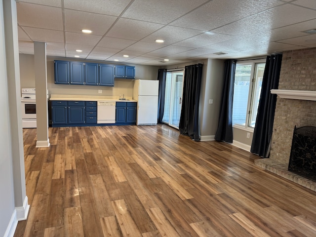 kitchen with dark wood-type flooring, white appliances, blue cabinets, and a fireplace