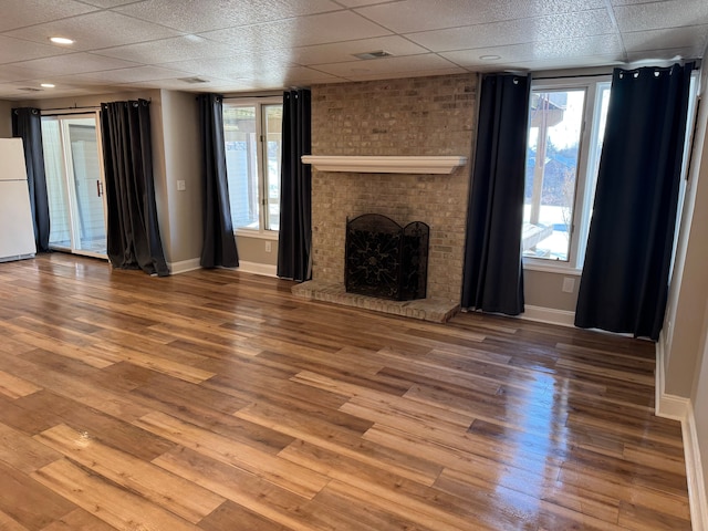 unfurnished living room with a brick fireplace, hardwood / wood-style flooring, and a healthy amount of sunlight