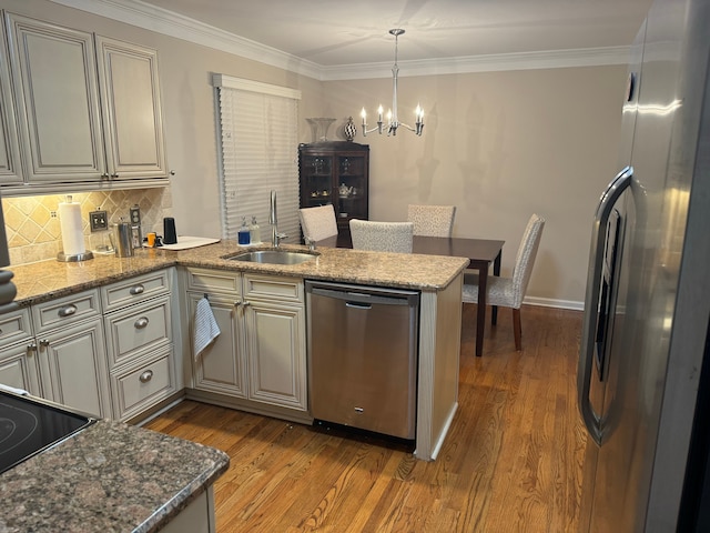 kitchen with sink, decorative light fixtures, appliances with stainless steel finishes, kitchen peninsula, and light stone countertops