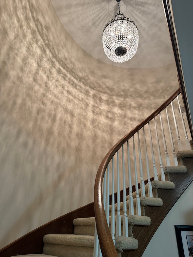 stairway featuring a notable chandelier