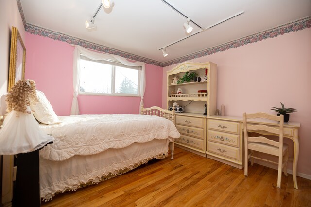 bedroom with rail lighting and light wood-type flooring