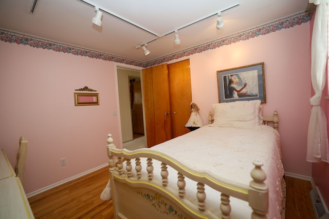 bedroom featuring track lighting, a closet, and light hardwood / wood-style flooring