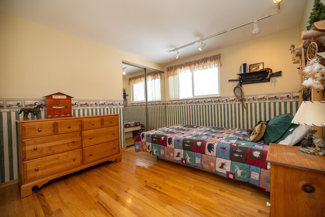 bedroom with a closet, track lighting, and light hardwood / wood-style flooring