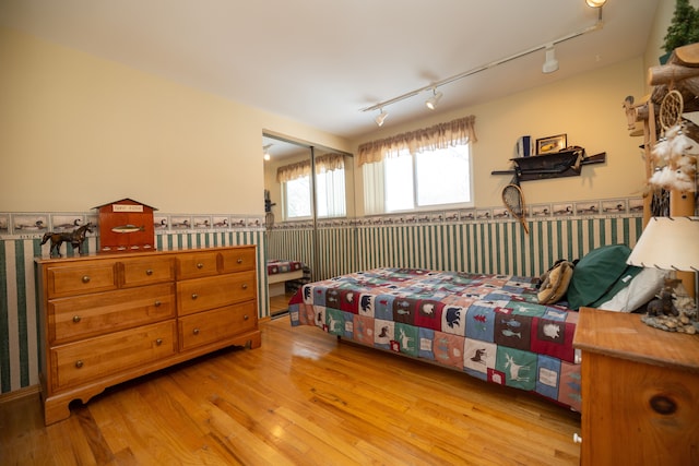 bedroom with rail lighting, a closet, and light wood-type flooring