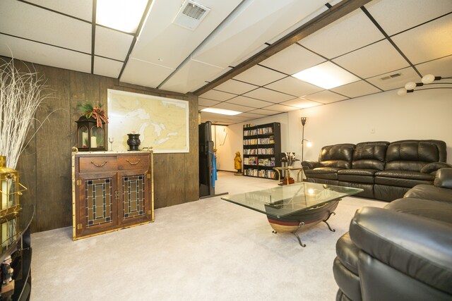 living room featuring light carpet, a drop ceiling, and wooden walls