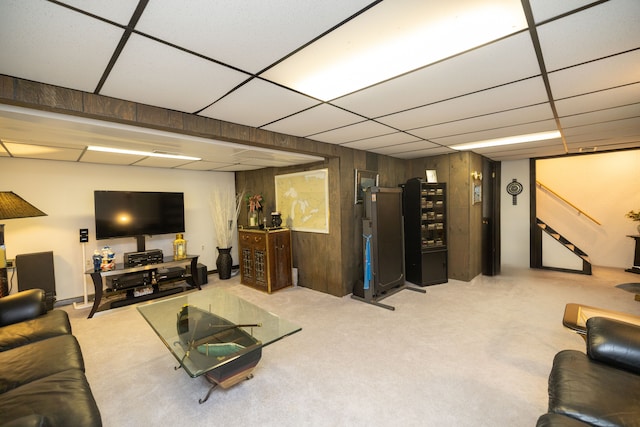 living room featuring a paneled ceiling and wood walls