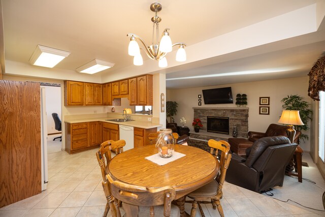 tiled dining space with a stone fireplace, sink, and an inviting chandelier