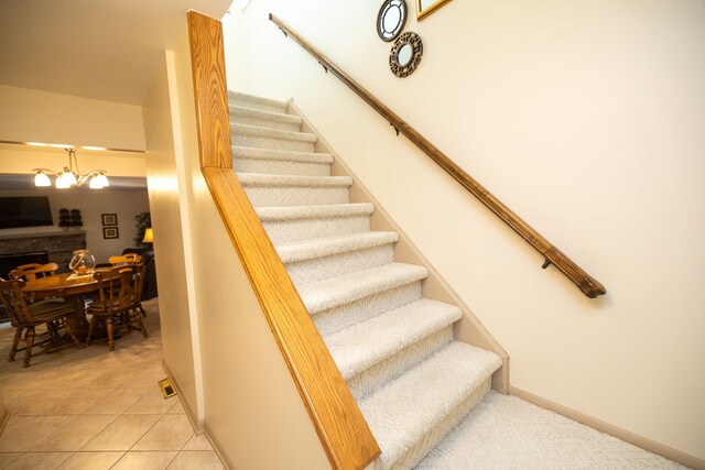 stairway with tile patterned floors and a chandelier