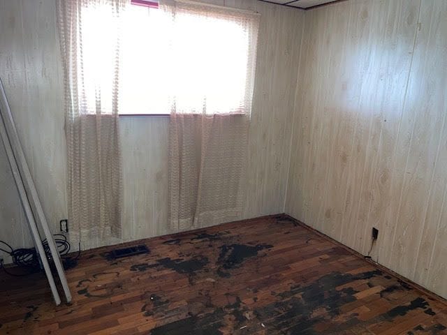 unfurnished room featuring dark hardwood / wood-style floors and wooden walls