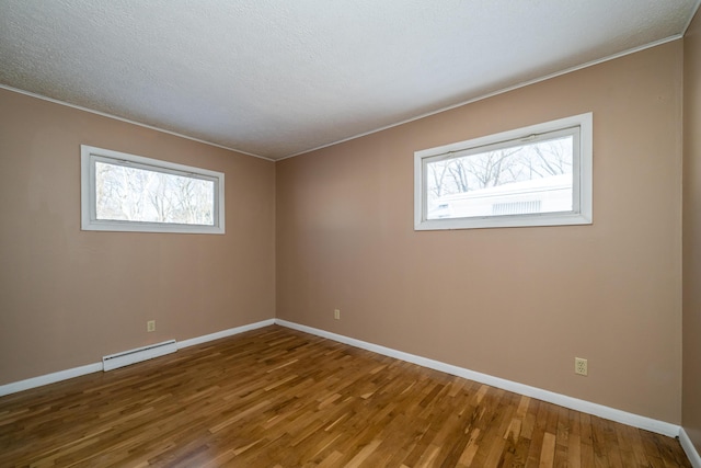 empty room with wood-type flooring and baseboard heating