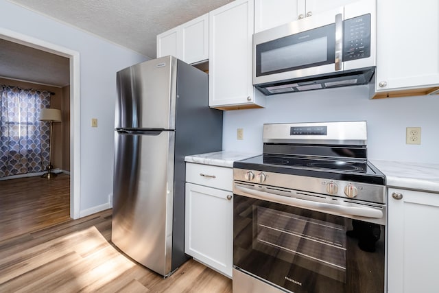 kitchen with stainless steel appliances, light stone countertops, a textured ceiling, and white cabinets