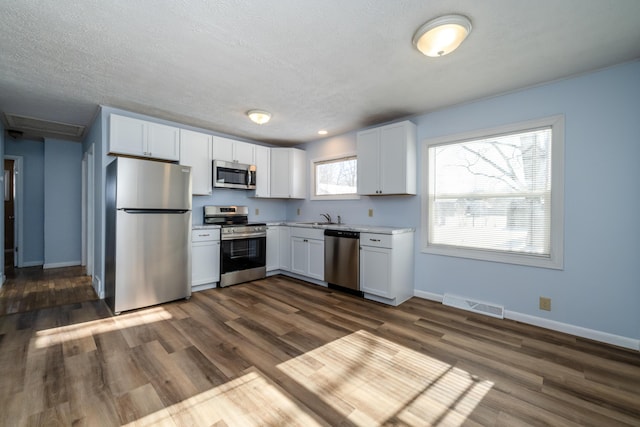 kitchen featuring dark hardwood / wood-style flooring, white cabinets, and appliances with stainless steel finishes