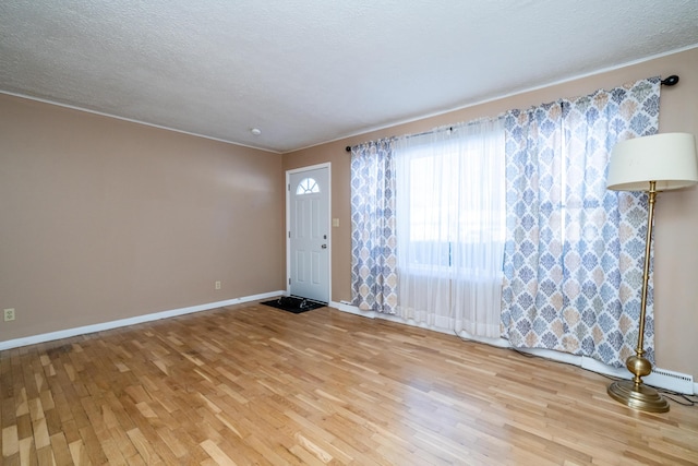 unfurnished room with a textured ceiling and light wood-type flooring