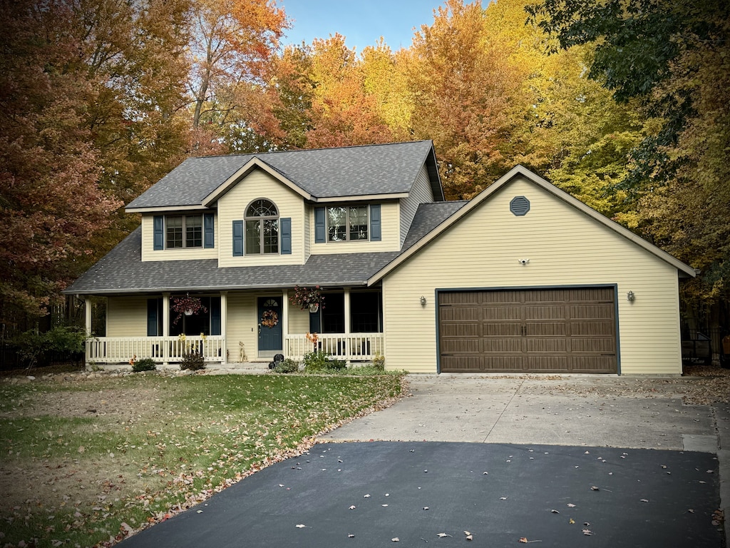 view of front of property featuring a garage, a front yard, and covered porch