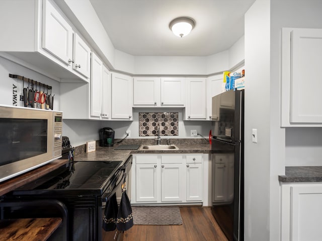 kitchen with white cabinetry, black refrigerator, and sink