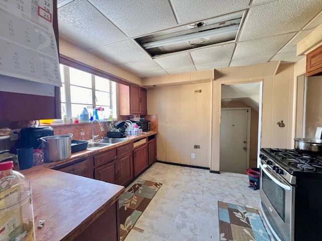 kitchen featuring a paneled ceiling, sink, and stainless steel gas stove