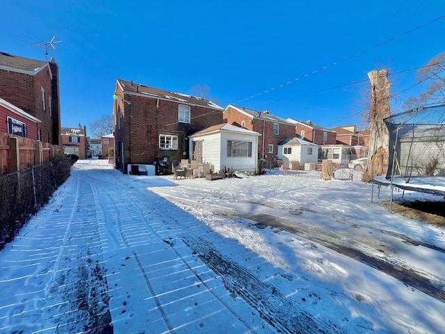 snow covered back of property with a trampoline