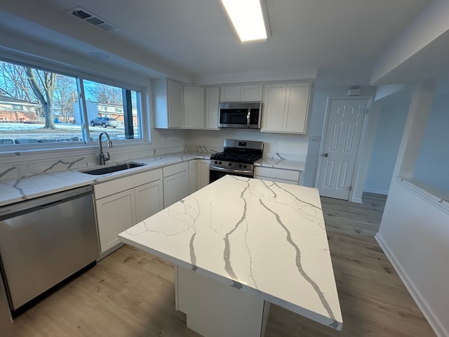 kitchen featuring stainless steel appliances, sink, a kitchen island, and white cabinets