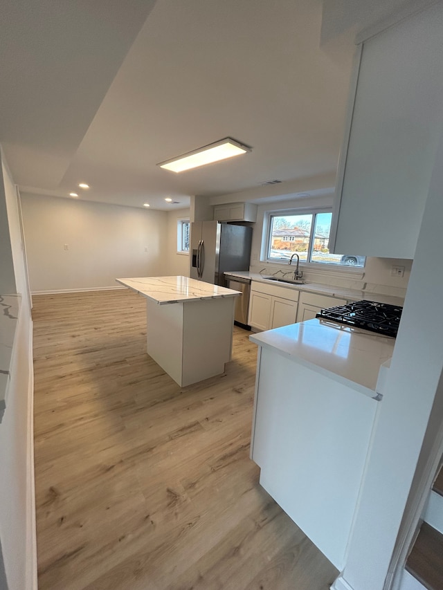 kitchen with sink, white cabinets, a center island, light hardwood / wood-style floors, and stainless steel appliances