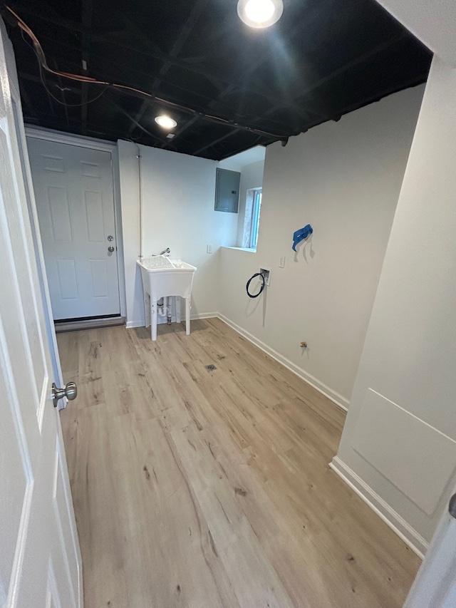 clothes washing area featuring hardwood / wood-style flooring and electric panel