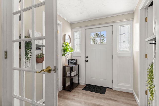 foyer with ornamental molding and light wood-type flooring