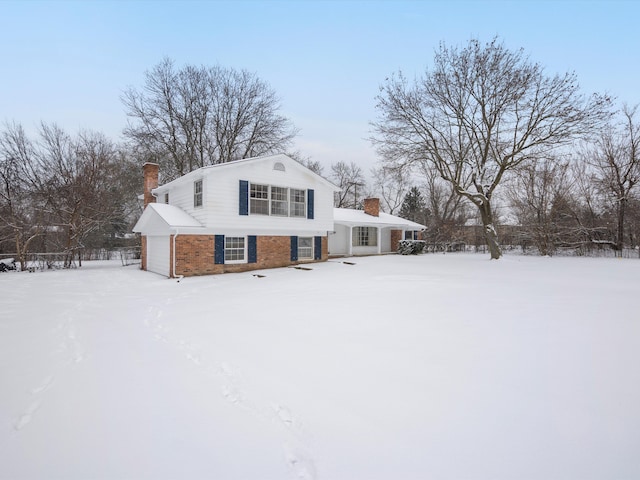 snow covered rear of property featuring a garage