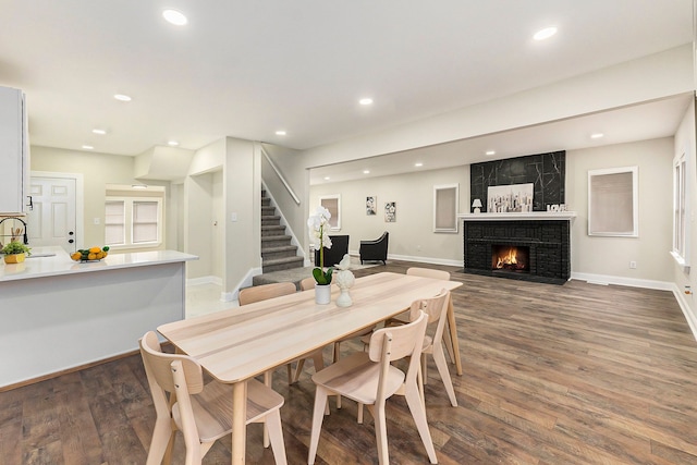 dining room featuring sink, dark wood-type flooring, and a fireplace