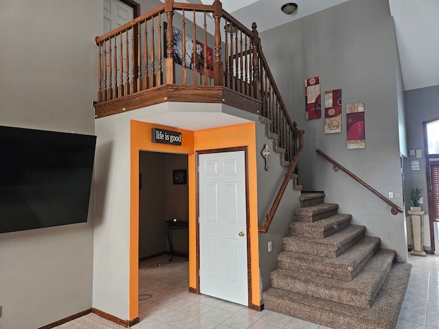 staircase with tile patterned floors and a high ceiling