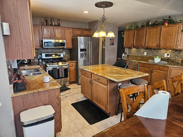 kitchen featuring pendant lighting, stainless steel appliances, light stone counters, and a kitchen island