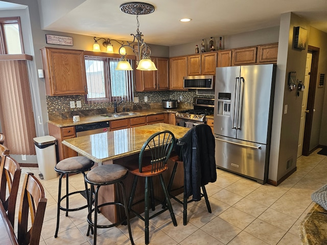 kitchen with appliances with stainless steel finishes, sink, decorative backsplash, hanging light fixtures, and a center island