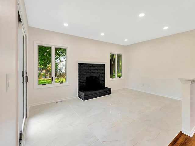 unfurnished living room featuring a brick fireplace and plenty of natural light