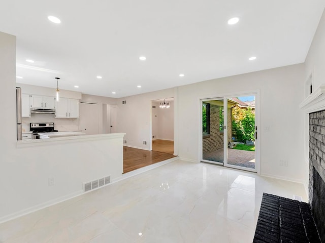 kitchen featuring a fireplace, decorative light fixtures, white cabinets, stainless steel range with electric stovetop, and kitchen peninsula