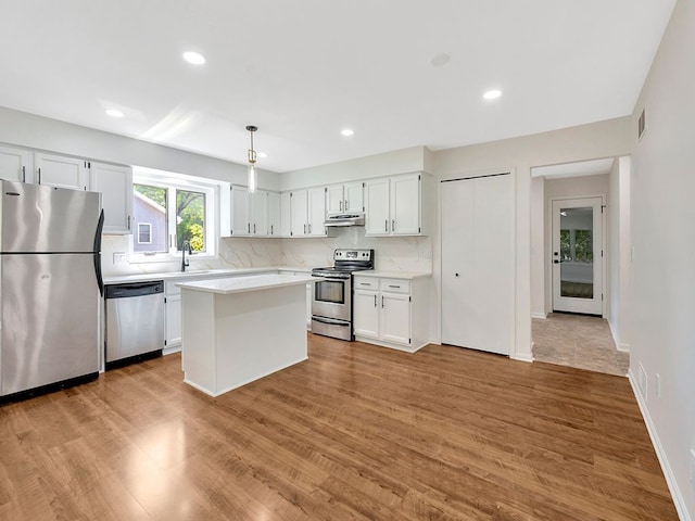 kitchen featuring tasteful backsplash, decorative light fixtures, white cabinets, and appliances with stainless steel finishes