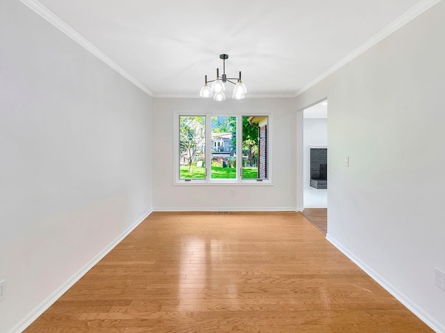 interior space featuring a notable chandelier, crown molding, light hardwood / wood-style flooring, and a brick fireplace