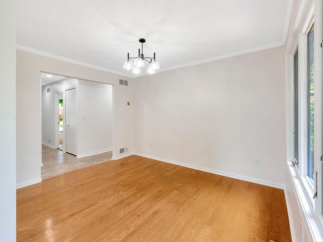 spare room featuring crown molding, a notable chandelier, and light hardwood / wood-style floors