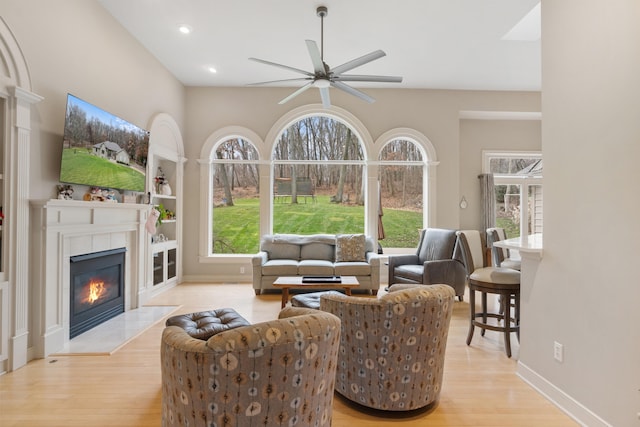 living room featuring a fireplace, light hardwood / wood-style floors, and ceiling fan