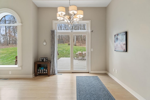 doorway featuring light hardwood / wood-style flooring and a chandelier