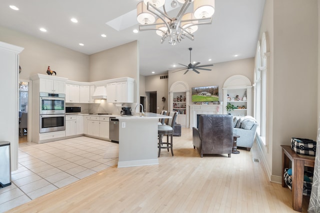 kitchen featuring a breakfast bar, appliances with stainless steel finishes, white cabinets, custom exhaust hood, and kitchen peninsula