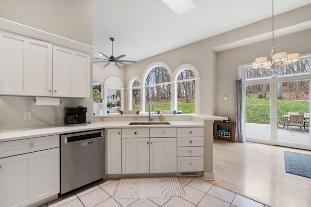 kitchen with pendant lighting, sink, white cabinets, light tile patterned flooring, and stainless steel dishwasher