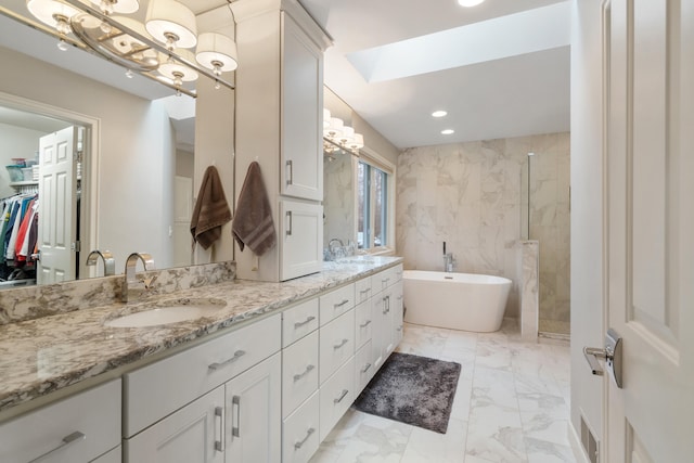 bathroom featuring plus walk in shower, vanity, and a skylight