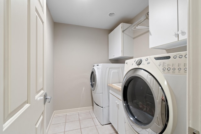 laundry room featuring cabinets, light tile patterned flooring, and washer and clothes dryer